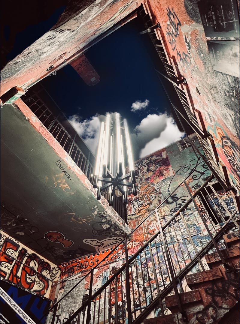 Stairwell sky — looking up through graffiti.